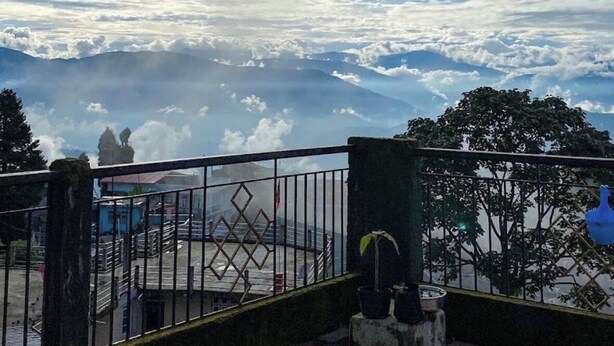Ein Balkon mit Metallgeländer und Blick auf eine gebirgige Landschaft.
