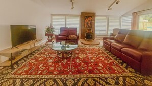 A living room with a large flat-screen TV, two leather sofas, a coffee table, and a patterned rug. - Entire 3-bedroom charming house in Lake Forest Park (Lake Forest Park)
