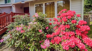 A house with a porch, a wooden staircase, and a garden with pink flowers. - Entire 3-bedroom charming house in Lake Forest Park (Lake Forest Park)