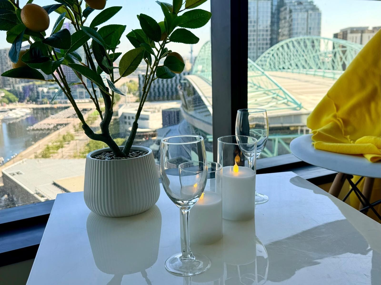 Una mesa con una planta en maceta, dos copas de vino y una vela encendida.