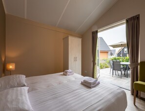 A hotel room with a bed, a wardrobe, and a view of the outdoor patio area. - Modern Villa With Garden (Almen)
