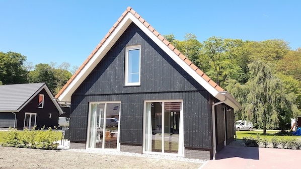 A modern building with a dark facade, large windows, and a sloped roof. - Modern Villa With Garden (Almen)