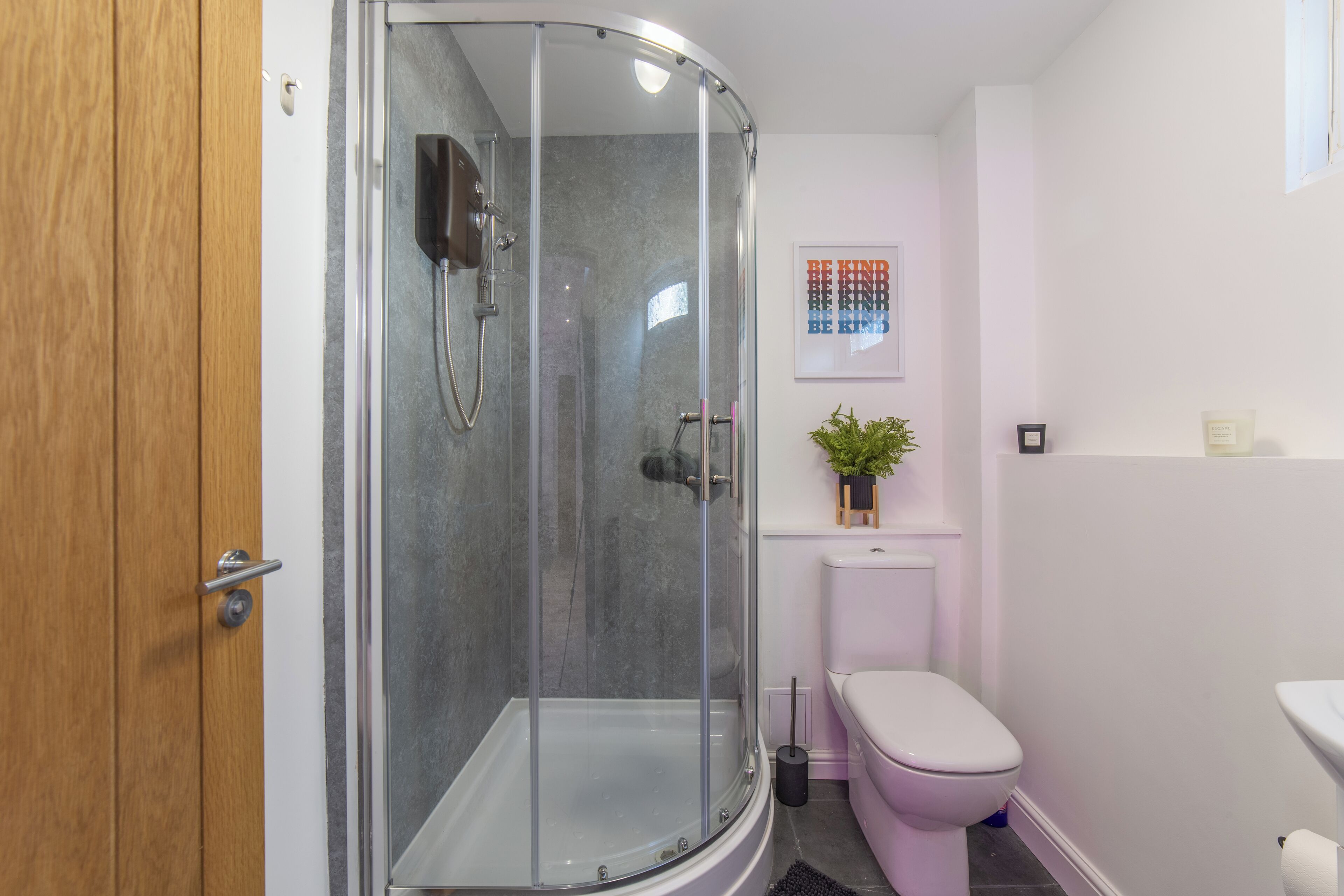 A modern bathroom with a glass-enclosed shower, a toilet, and a sink.