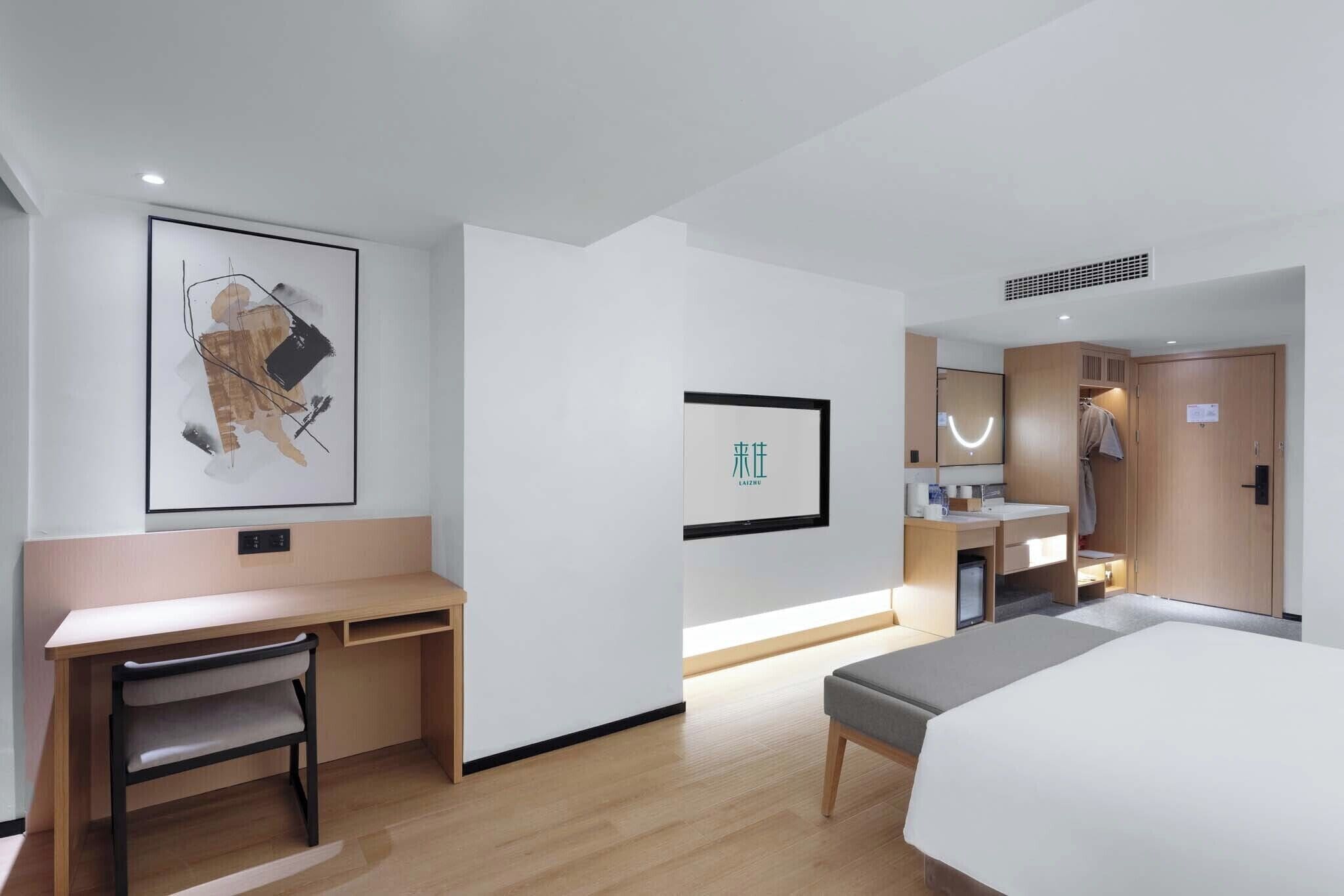 Ein Hotelzimmer mit Bett, Schreibtisch, Stuhl, Nachttisch, Kleiderschrank und Badezimmer.