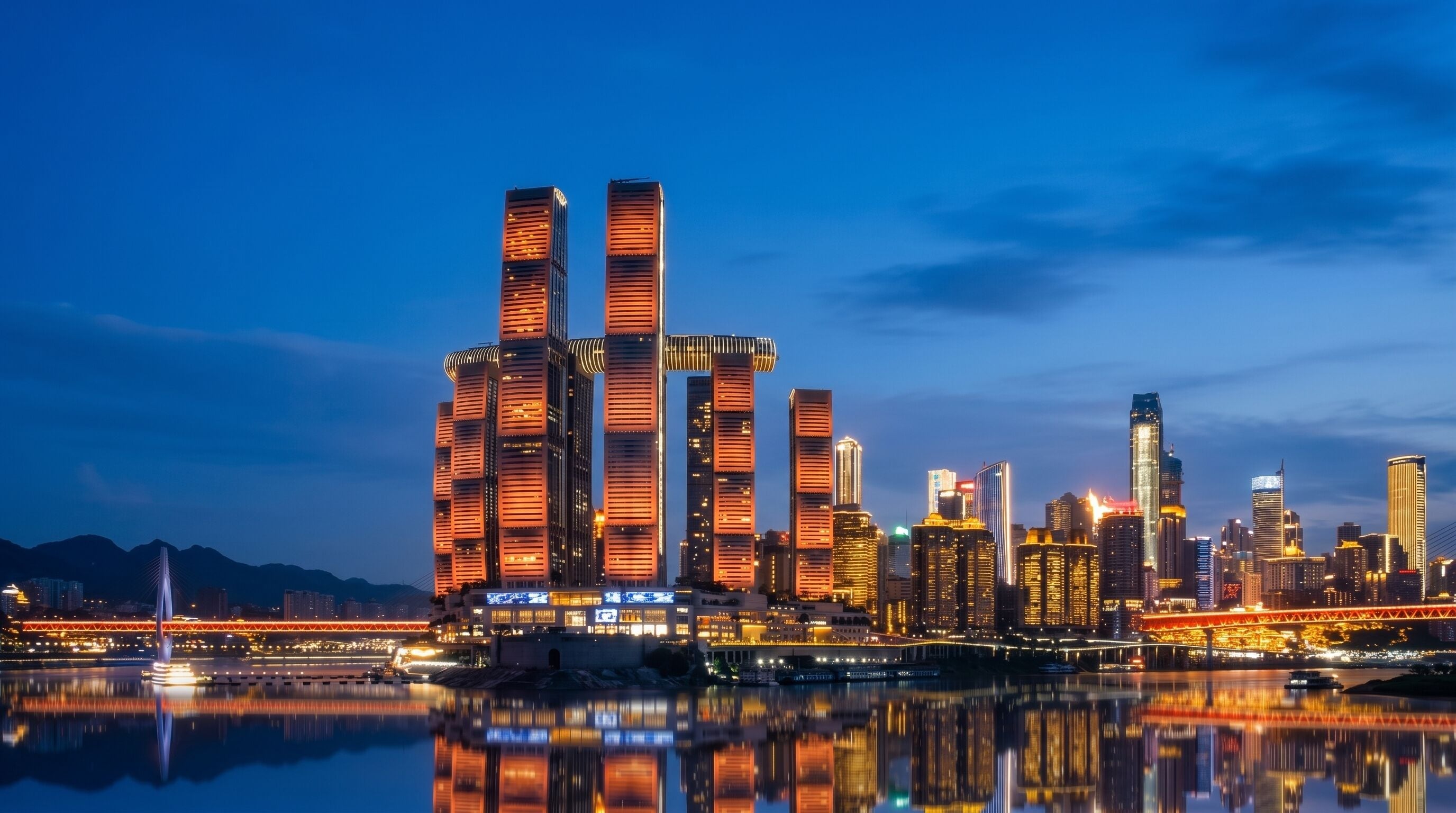 A city skyline with modern high-rise buildings, a river reflecting the lights, and a bridge in the foreground.