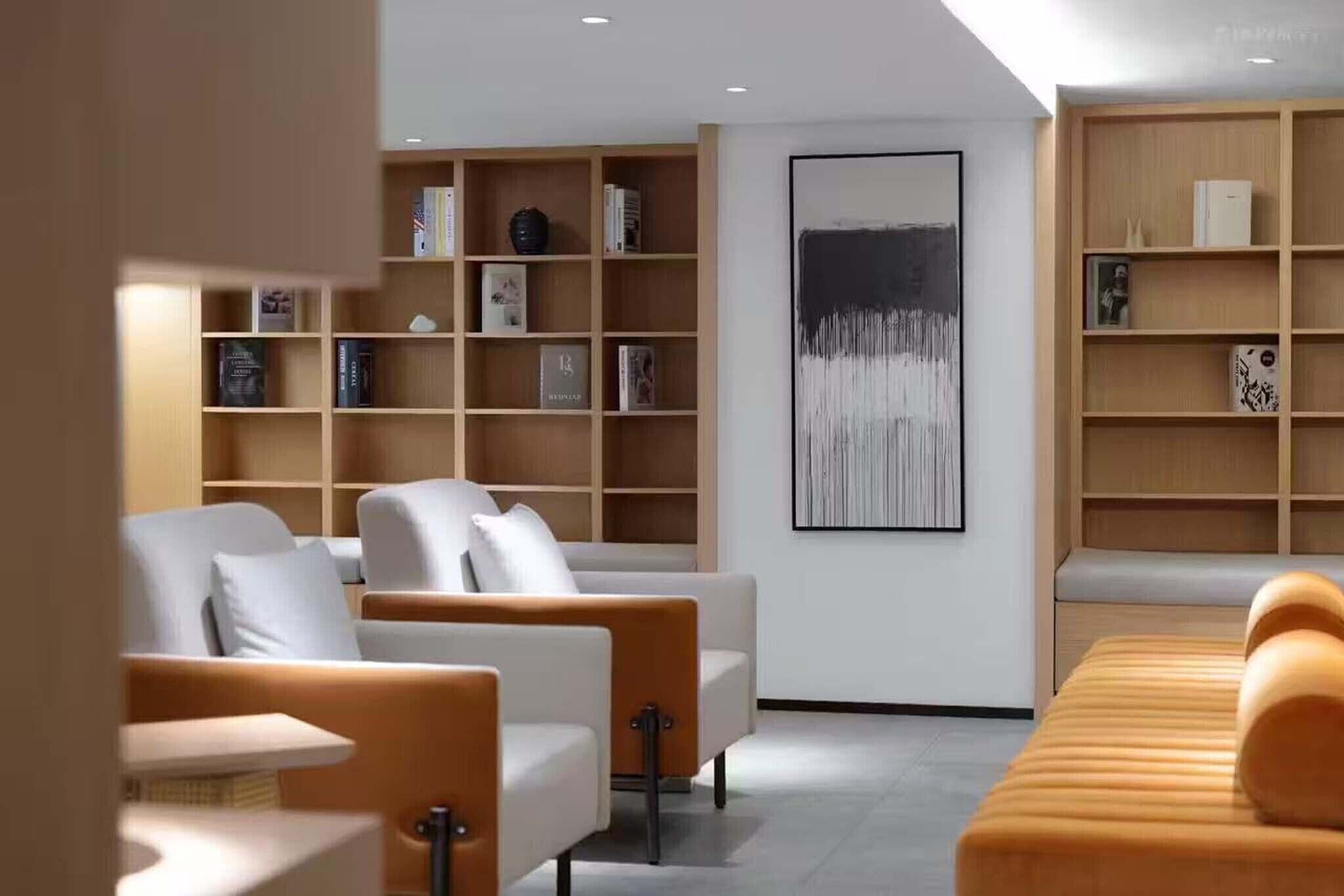 Una sala de estar moderna con un conjunto de sofás, una mesa de centro y dos estanterías de madera llenas de libros y objetos decorativos.