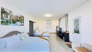 A hotel room with two beds, a TV, a desk, and artwork on the walls. - Oasis Phamee (Mae Sai)