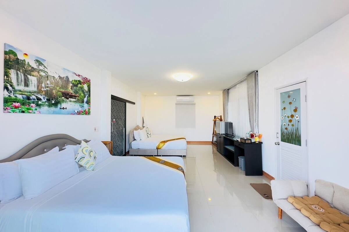 A hotel room with two beds, a TV, a desk, and artwork on the walls.