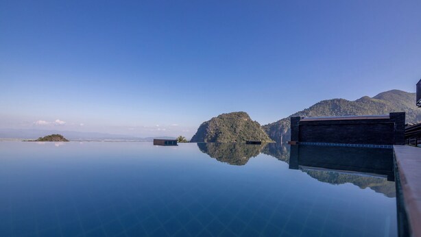 A serene infinity pool reflecting a mountainous landscape. - Oasis Phamee (Mae Sai)