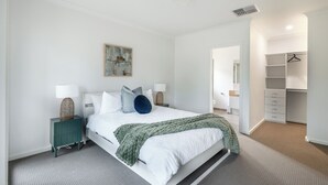 Een slaapkamer met een bed, nachtkastjes, een kledingkast en een schilderij aan de muur.
