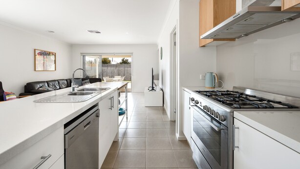 Een moderne keuken met witte kasten, roestvrijstalen apparatuur en een groot raam dat voor natuurlijk licht zorgt.