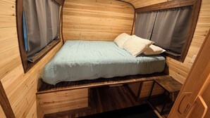 A compact, wooden interior with a bed, curtains, and a small table. - Birch Bus in North Pole (North Pole)