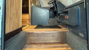 A narrow, wooden interior with a metal staircase leading to a higher level. - Birch Bus in North Pole (North Pole)