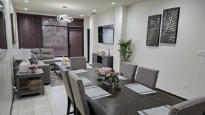 Uma sala de estar moderna com sofá, mesa de centro e mesa de jantar para seis pessoas.