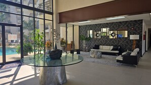 Un hall d’entrée moderne avec une table en verre, un espace salon et une vue sur une piscine.