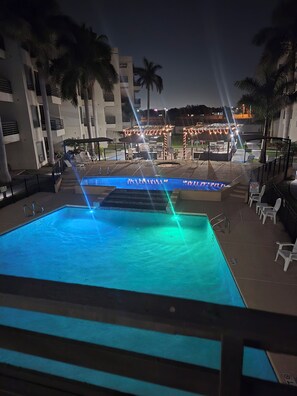 A swimming pool with a water feature, surrounded by palm trees and a building with outdoor seating. - Spacious 3Bedroom Apartment in Gated Community Prime Location, 1Mi from Shopping (Mission)