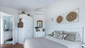 Ein Schlafzimmer mit einem Bett, einer Kommode, einem Spiegel und zwei Wandbildern.