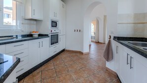 Eine moderne Küche mit weißen Schränken, einem Einbauofen, einer Mikrowelle und einem großen Fenster.