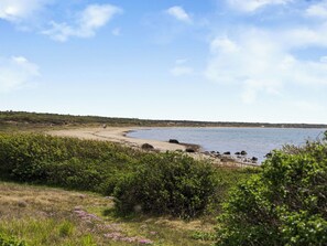 A coastal landscape with a sandy beach, dense greenery, and a calm sea under a clear sky. - Villshärad by Interhome (Halmstad)