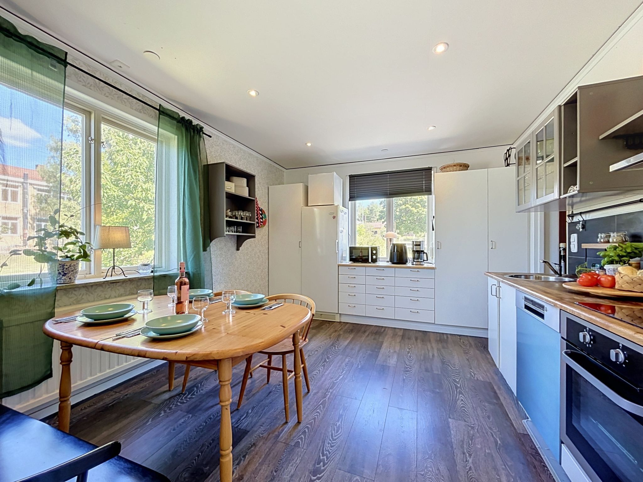 Une cuisine moderne avec un coin repas, un plancher en bois et une vue sur l’extérieur.