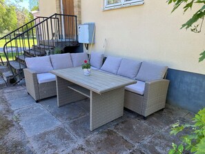 Une terrasse avec des meubles en osier, une table et une plante en pot.