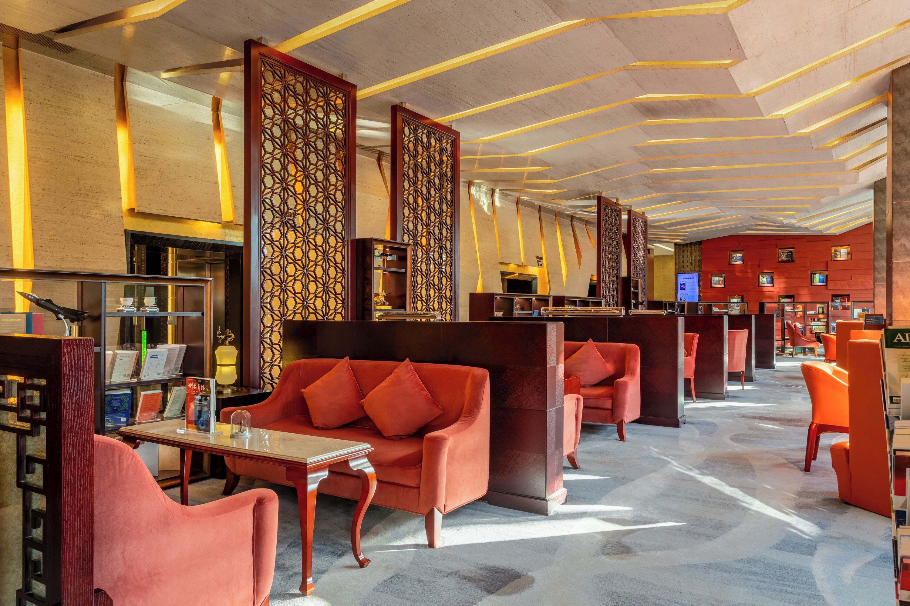 A hotel lobby with a modern design, featuring a reception desk, seating areas, and a patterned wall.