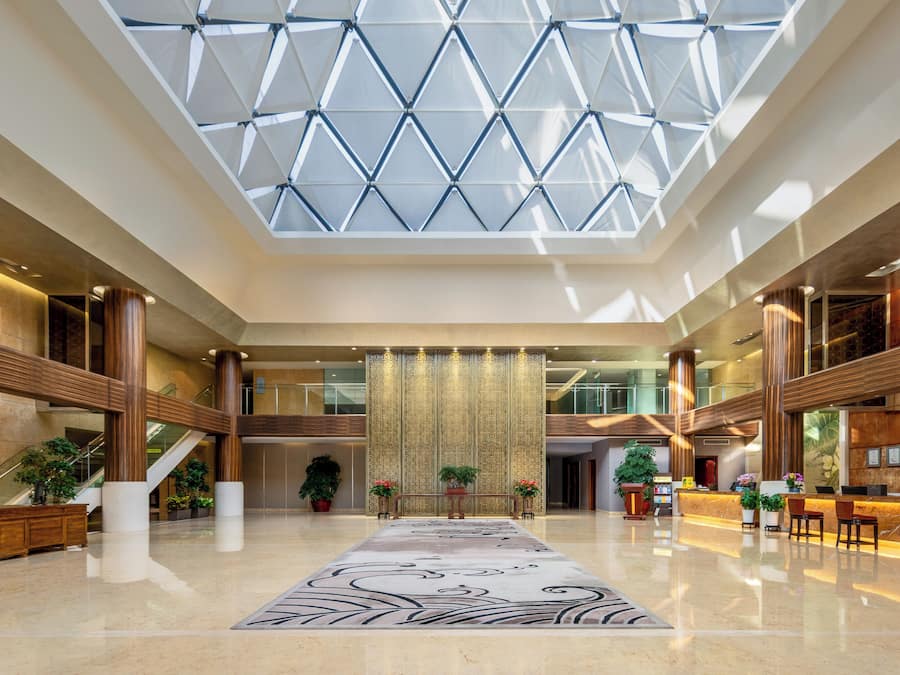 Un vestíbulo amplio con techo alto, un panel decorativo central y un mostrador de recepción.