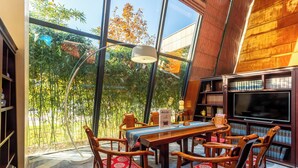Ein Essbereich mit großem Fenster, Holzmöbeln und einem Fernseher.