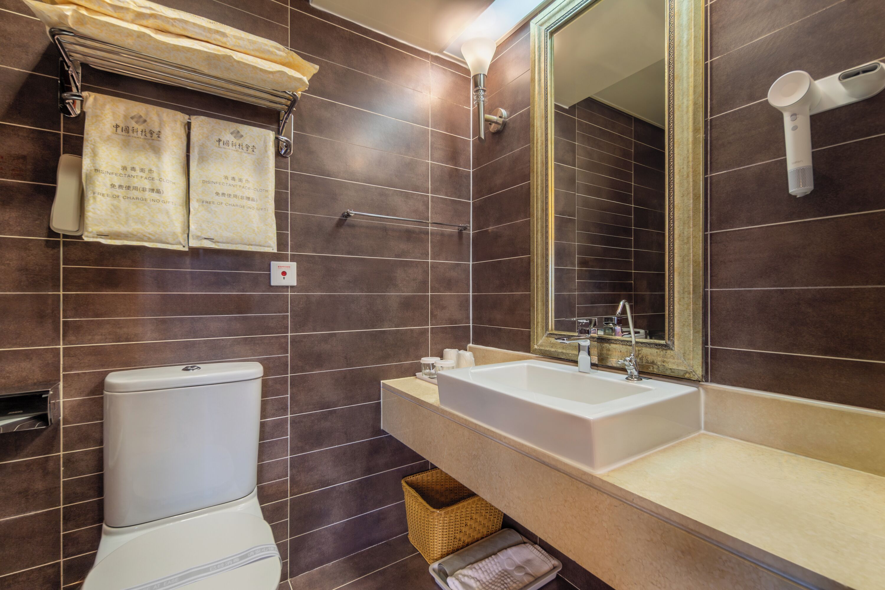 Ein Badezimmer mit Toilette, Waschbecken, Spiegel, Handtuchhalter und einem Fön.