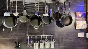 A kitchen with hanging pots and pans, a knife block, and a tray.