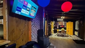 A cozy room with a large flat-screen TV displaying various streaming services, a black bean bag chair, and a checkered floor.