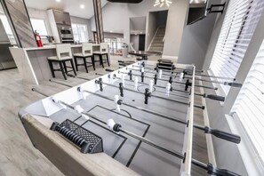 A modern indoor space with a foosball table, bar area, and a staircase. - Villa in the HEART of town (Las Vegas)