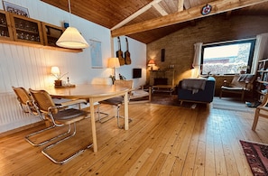 A cozy room with a wooden dining table, chairs, a sofa, and a fireplace. - Charming and cozy cottage (Tranekær)