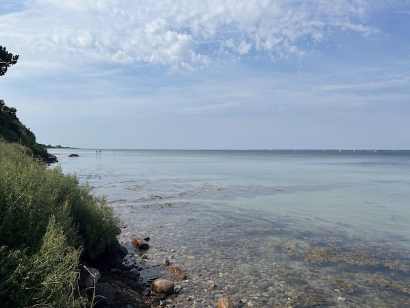 A clear coastal view with calm waters, rocky shoreline, and distant land. - Charming and cozy cottage (Tranekær)
