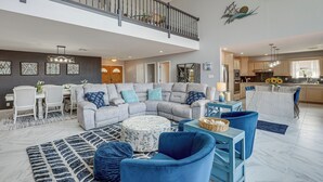 A spacious living room with a grey sectional sofa, blue armchairs, and a round ottoman. A dining area with a white table and chairs is visible in the background. - Panoramic Lake Belton Views: Home Near Marina (Belton)