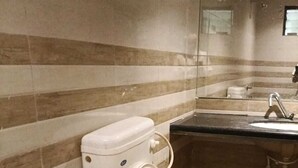 Een badkamer met toilet, wastafel en spiegel.