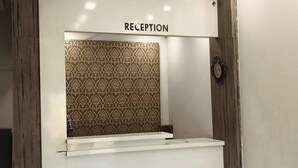 Een receptiegedeelte met een 'RECEPTION' bord, een decoratieve achtergrond en een houten accentmuur.