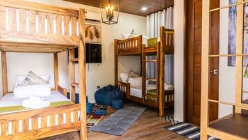 A room with two bunk beds, a wooden ceiling, a hanging light fixture, and a patterned rug.