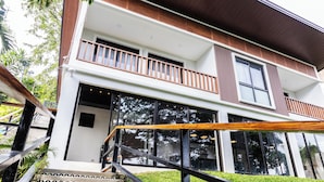 Ein zweistöckiges Gebäude mit Balkon, großen Fenstern und einer Treppe mit gemusterten Fliesen.