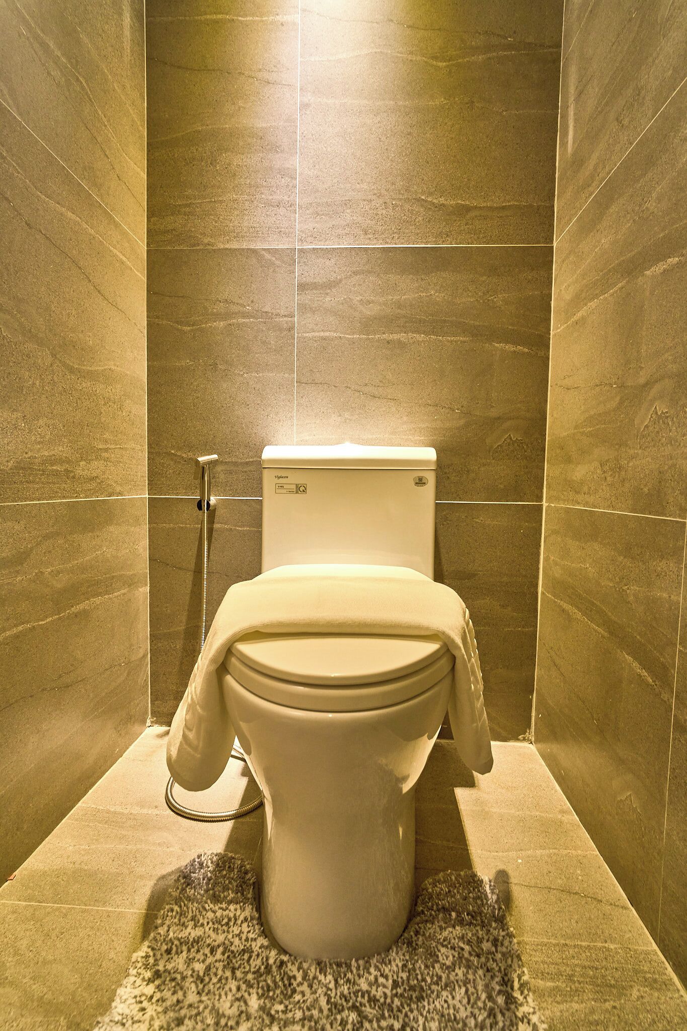 A bathroom with a toilet, shower, and tiled walls.