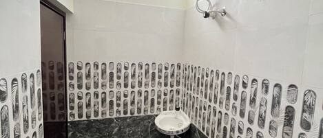 Une salle de bain équipée d’un lavabo, de toilettes, d’une douche et d’un chauffe-eau fixé au mur.