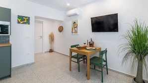A compact living space with a dining area, a TV mounted on the wall, and a potted plant. - Apartments with pool on the Makarska Riviera near the sea (Zaostrog)
