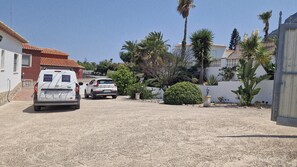 A residential area with a white van parked in front of a house with a red-tiled roof. There are palm trees and a small garden with a fountain. - Casa Menta Denia - Denia, Costa Blanca (Denia)