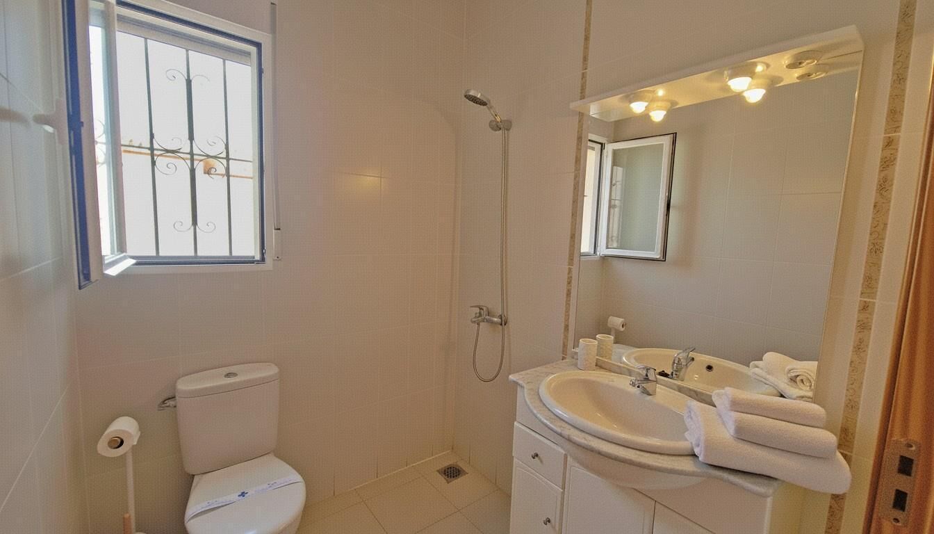 A bathroom with a toilet, shower, sink, and mirror.