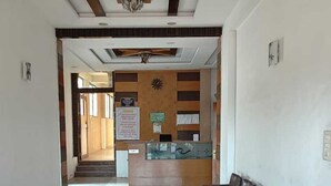 Zona de recepción de un hotel, con mostrador, un reloj y una fila de sillones de cuero.