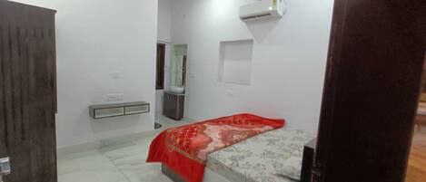 A bedroom with a bed, a bedside table, a mirror, and a wall-mounted air conditioner.