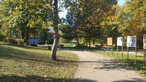Ein gepflasterter Weg in einem Park mit Bäumen und Bänken.