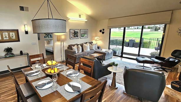 Un vaste espace de vie comprenant une table à manger pour quatre personnes, un canapé et un balcon avec des sièges d’extérieur.