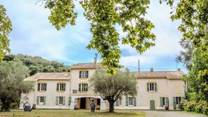 A two-story building with a tiled roof, green shutters, and a central entrance.