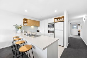 Eine moderne Küche mit einer zentralen Kochinsel, Barhocker, einer Mikrowelle, einem Backofen und einem Kühlschrank.